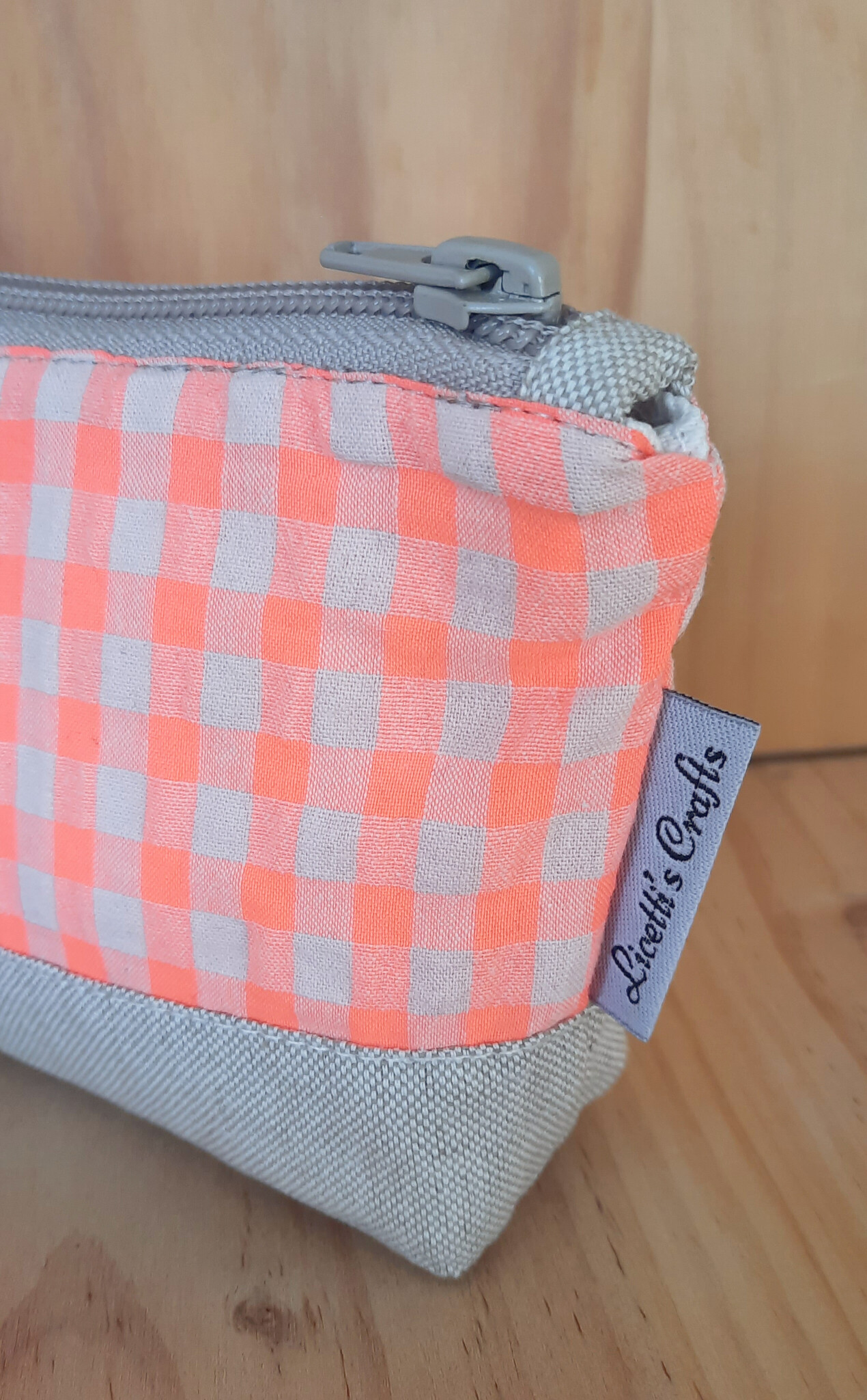 Detalle de los cuadros vichy naranja flúor y la base de tejido natural del estuche.